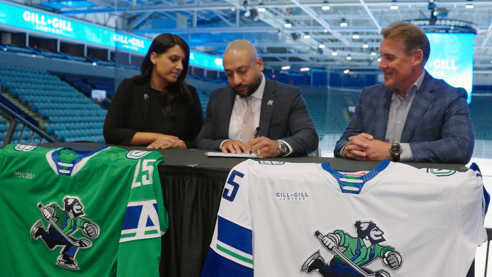 law firm representatives signing a partnership agreement during a sports sponsorship event with team jerseys displayed